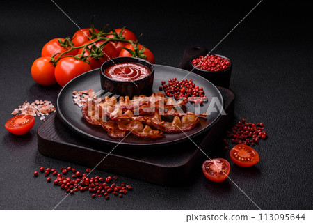 Delicious fresh fried bacon with salt and spices on a dark background 113095644