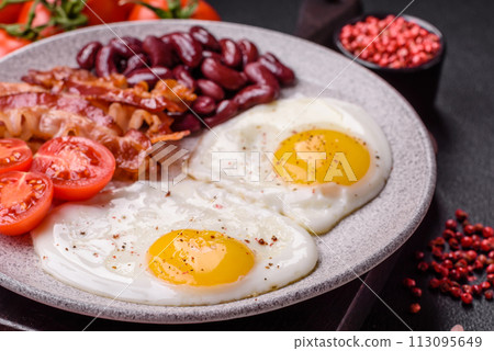 English breakfast with fried eggs, bacon, beans, tomatoes, spices and herbs 113095649