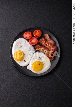 English breakfast with fried eggs, bacon, beans, tomatoes, spices and herbs 113095658