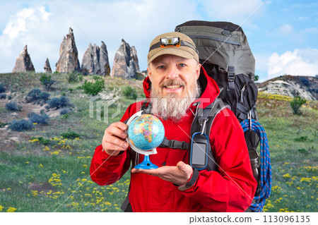 bearded tourist in a red jacket holds a model of the world globe in his hands 113096135
