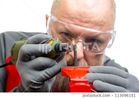 Bearded man mechanic processes metal with an engraving drill. Locksmith industry. 113096181