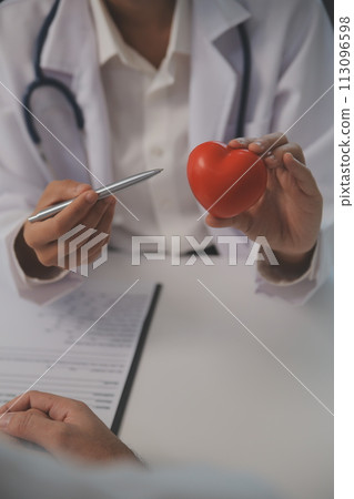Hands of doctor woman holding red heart, showing symbol of love, human support to patient, promoting medical insurance, early checkup for healthcare, cardiologist help. Close up of object 113096598