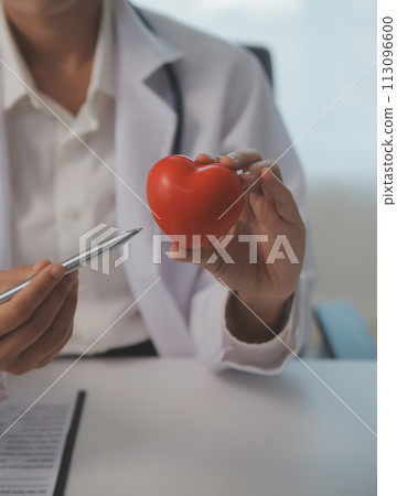 Hands of doctor woman holding red heart, showing symbol of love, human support to patient, promoting medical insurance, early checkup for healthcare, cardiologist help. Close up of object 113096600