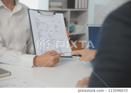 Close up view of job interview in office, focus on resume writing tips, employer reviewing good cv of prepared skilled applicant, recruiter considering application, hr manager making hiring decision 113096635