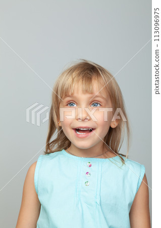 Joyful little girl smiling against a grey background Joyful little girl smiling against a grey background 113096975