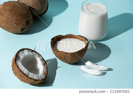 Healthy vegan coconut milk in coconut shell on blue background. Healthy vegan coconut milk in coconut shell on blue background. 113097081