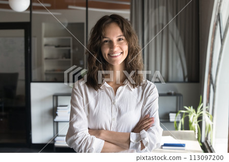 Happy young professional woman in white shirt standing in office 113097200