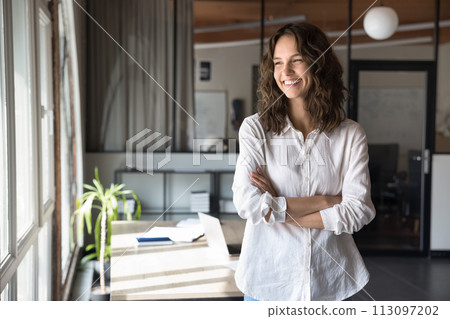 Cheerful young business professional woman in casual standing in office Cheerful young business professional woman in casual standing in office 113097202