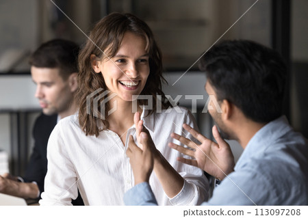 Happy young Caucasian businesswoman enjoying professional discussion with Indian coworker Happy young Caucasian businesswoman enjoying professional discussion with Indian coworker 113097208