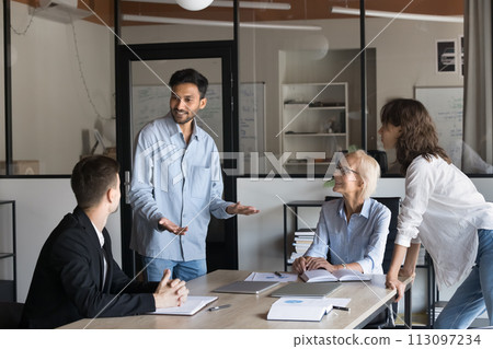 Happy young Indian manager speaking to colleagues, offering creative ideas 113097234