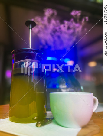 Tea cup and teapot with matcha tea on wooden table in cafe 113097506