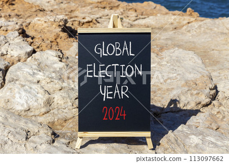 Global election year 2024 symbol. Concept words Global election year 2024 on beautiful black blackboard. Beautiful stone blue sea sky background. Business Global election year 2024 concept. Copy space 113097662