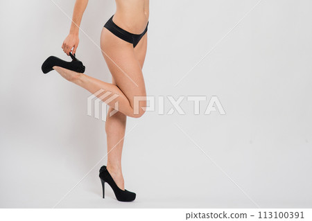 Cute brunette female model posing, wearing black and red underwear in white studio 113100391