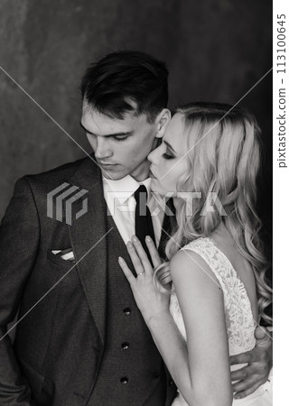 Cute wedding couple in the interior of a classic studio decorated. They kiss and hug each other. 113100645