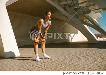 Young female athlete in sportswear have a rest after morning jogging outside and looks away 113101037