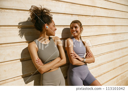 Smiling female sportswomen with crossed hands have a rest after morning jogging outdoors  113101042
