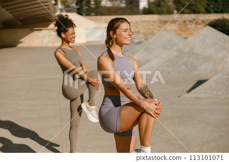 Athletic women in sportswear are stretching legs before doing workout outside in morning 113101071