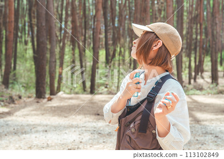 一名婦女在露營地使用驅蟲噴霧和防曬噴霧 113102849