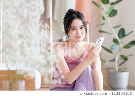 Young woman looking at her smartphone in the living room 113104108