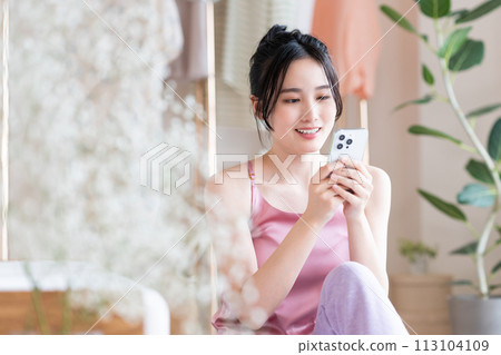 Young woman looking at her smartphone in the living room Young woman looking at her smartphone in the living room 113104109