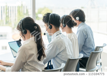 Male and female operators answering the phone at a call center 113104773