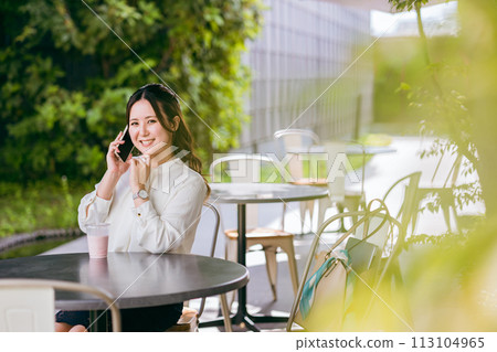 A young Asian business woman talking on a smartphone at a terrace seat 113104965
