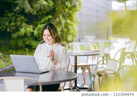 A business woman (nomad worker) doing nomad work on the terrace of a cafe A business woman (nomad worker) doing nomad work on the terrace of a cafe 113104974