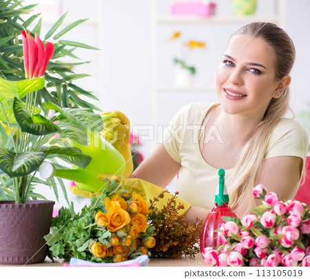 Young woman watering plants in her garden Young woman watering plants in her garden 113105019