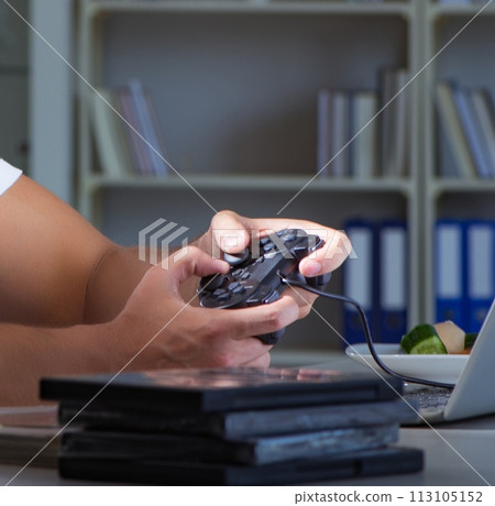 Young man playing games long hours late in the office 113105152