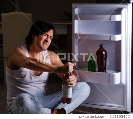Man breaking diet at night near fridge Man breaking diet at night near fridge 113105433