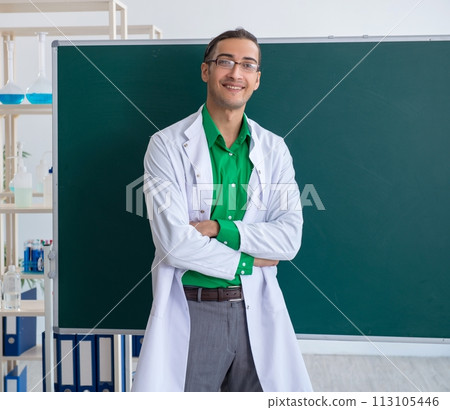 Young male chemist teacher in front of blackboard 113105446