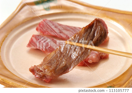 An image of grasping delicious-looking meat dishes, delicious-looking beef steaks, and beef with chopsticks 113105777
