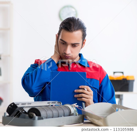 Young repairman repairing air-conditioner at warranty center Young repairman repairing air-conditioner at warranty center 113105986