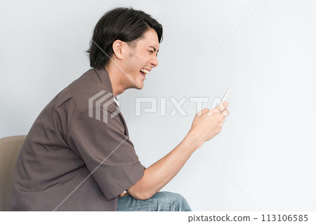 使用智慧型手機的年輕亞洲男子(直頸、捲肩、駝背、乾眼、智慧型手機老花眼、眼睛疲勞) 使用智慧型手機的年輕亞洲男子(直頸、捲肩、駝背、乾眼、智慧型手機老花眼、眼睛疲勞) 113106585