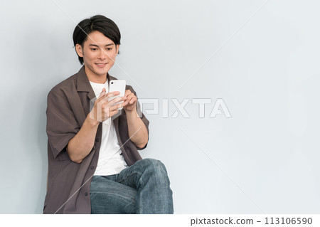 Young Asian man using a smartphone (searching/investigating) 113106590