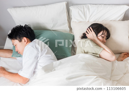 A wife who is sleep deprived due to her husband's snoring and sleep talking in bed (insomnia, noisy noise, stress, disturbed sleep) 113106605