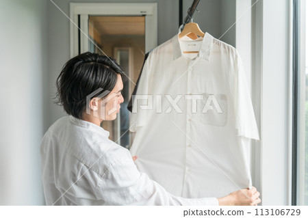 A man drying laundry in the laundry room (wrinkle smoothing, househusband, indoor drying)) 113106729