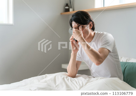 A young Asian man apologizes via smartphone for oversleeping, being late, oversleeping, and oversleeping in the morning. A young Asian man apologizes via smartphone for oversleeping, being late, oversleeping, and oversleeping in the morning. 113106779