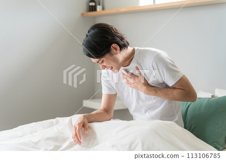一名突發疾病的男子在床上患有胸痛（疼痛、癲癇發作、心肌梗塞、心臟病發作、心悸、心絞痛） 113106785
