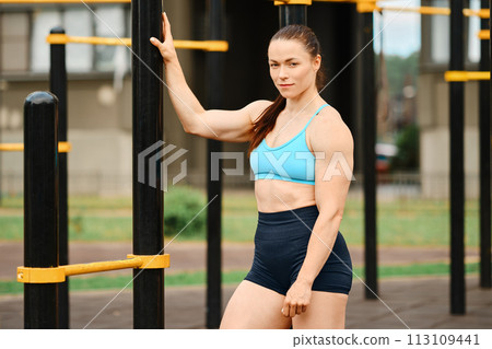 Muscular woman stands near horizontal bar 113109441