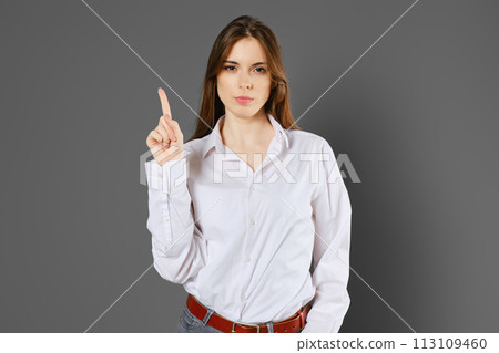Serious woman shows one index finger Serious woman shows one index finger 113109460