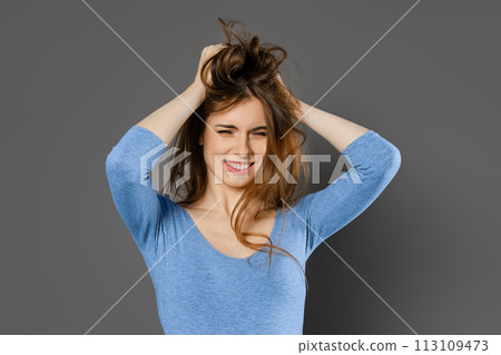 Young woman fooling around and mussing her hair with her hands Young woman fooling around and mussing her hair with her hands 113109473