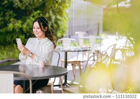 一位年輕女性/女商人在咖啡館使用智慧型手機（SNS、應用程式、聊天、線上購物） 113110322
