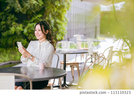 一位年輕女性/女商人在咖啡館使用智慧型手機（SNS、應用程式、聊天、線上購物） 113110323