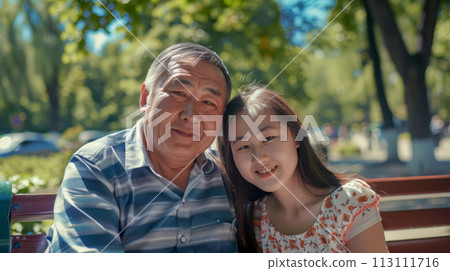 Adult father with younger daughter on park bench, portrait of happy central asian family, caring concept and Father's Day poster 113111716