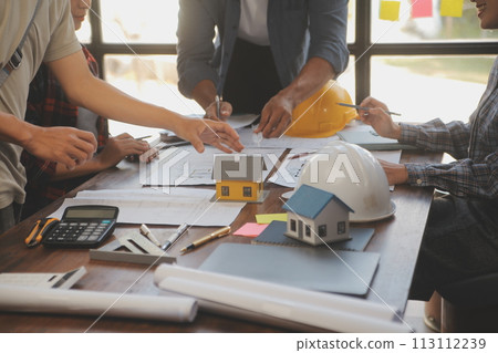 A team of construction engineers talks to managers and construction workers at the construction site. Quality inspection, work plan, home and industrial building design project 113112239