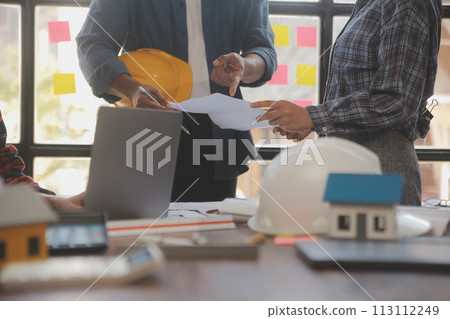 A team of construction engineers talks to managers and construction workers at the construction site. Quality inspection, work plan, home and industrial building design project A team of construction engineers talks to managers and construction workers at the construction site. Quality inspection, work plan, home and industrial building design project 113112249