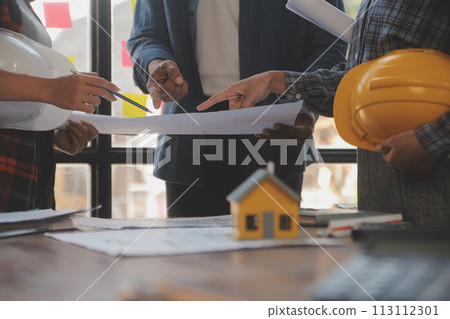 A team of construction engineers talks to managers and construction workers at the construction site. Quality inspection, work plan, home and industrial building design project 113112301