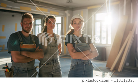 A team of painters in the backlight of the sun and space for a concept, arms crossed and seriously looking into the frame, pride in work and labor day poster idea A team of painters in the backlight of the sun and space for a concept, arms crossed and seriously looking into the frame, pride in work and labor day poster idea 113112353