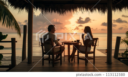 A date in a cafe, a silhouette of newlyweds at a table in a restaurant, a beautiful couple with glasses of wine enjoying a conversation and admiring the beautiful sunsets at sea 113112380